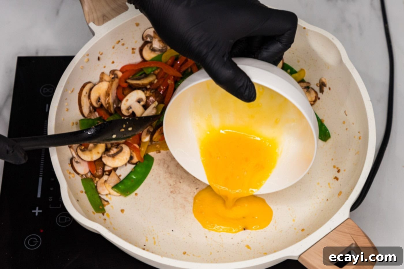 Savory Vegetable Lo Mein 7 Whisked egg being poured into the empty side of a skillet with vegetables