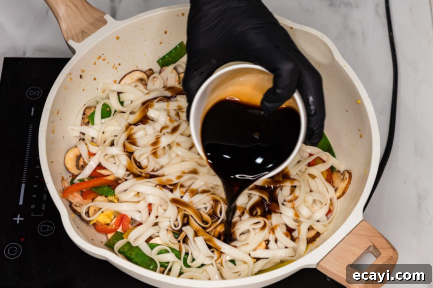 Savory Vegetable Lo Mein 9 Sauce being poured into a skillet with vegetable lo mein, ready to be tossed