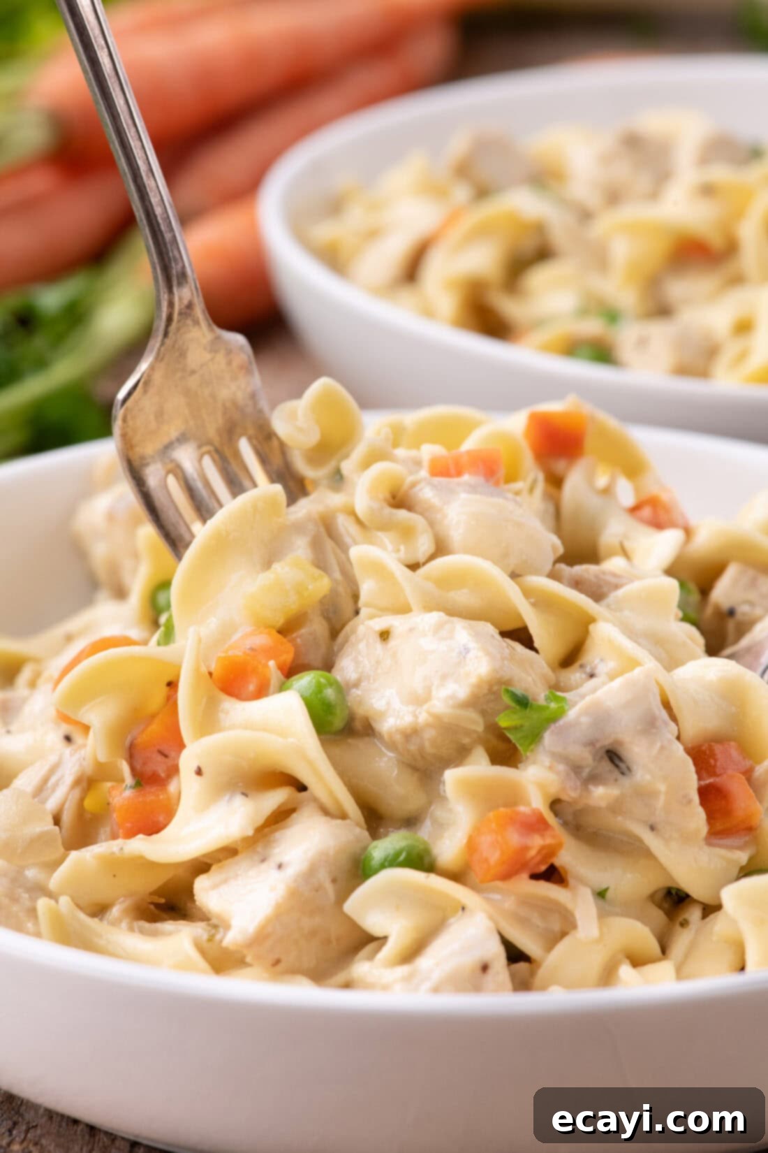 Hearty Chicken Pot Pie Pasta 12 Fork digging into a bowl of Creamy Chicken Pot Pie Pasta, highlighting the rich sauce and ingredients