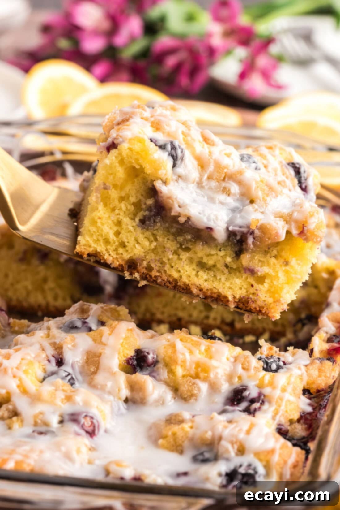 Tender Blueberry Cake with Zesty Lemon Glaze 11 Slice of Glazed Lemon Blueberry Cake being lifted out of the dish
