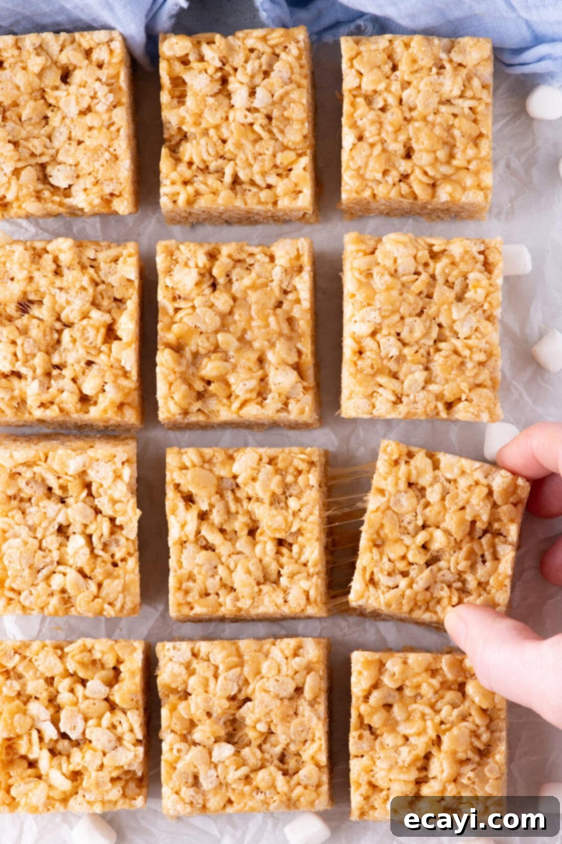 Crunchy Peanut Butter Krispie Delights 3 Peanut Butter Rice Krispie Treats expertly cut into perfect squares, resting on parchment paper for easy handling.