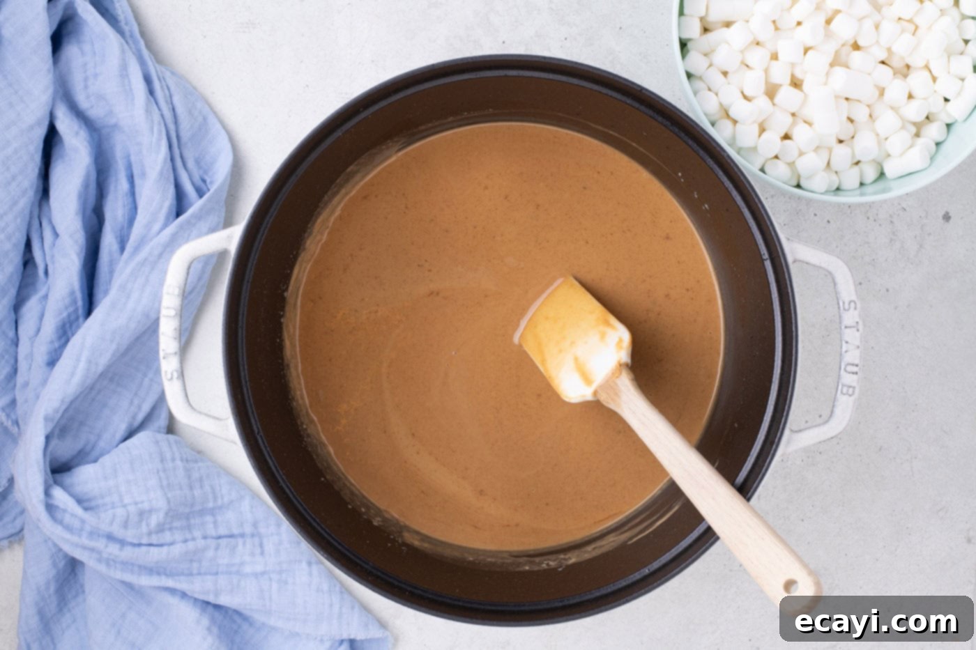 Crunchy Peanut Butter Krispie Delights 6 Creamy peanut butter being stirred into melted butter and vanilla in a pot with a rubber spatula, creating a smooth mixture.