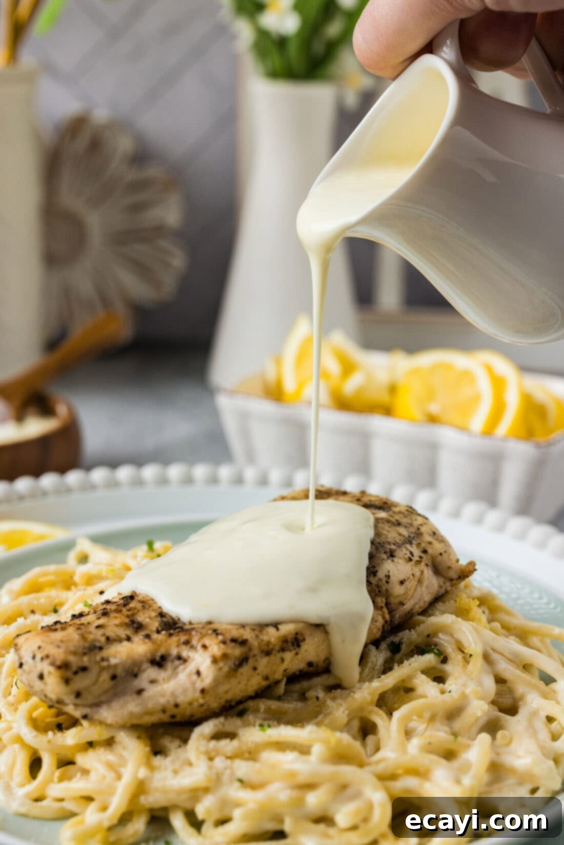 Zesty Lemon Cream 2 Lemon Cream Sauce being poured over a chicken breast, showcasing its vibrant texture.