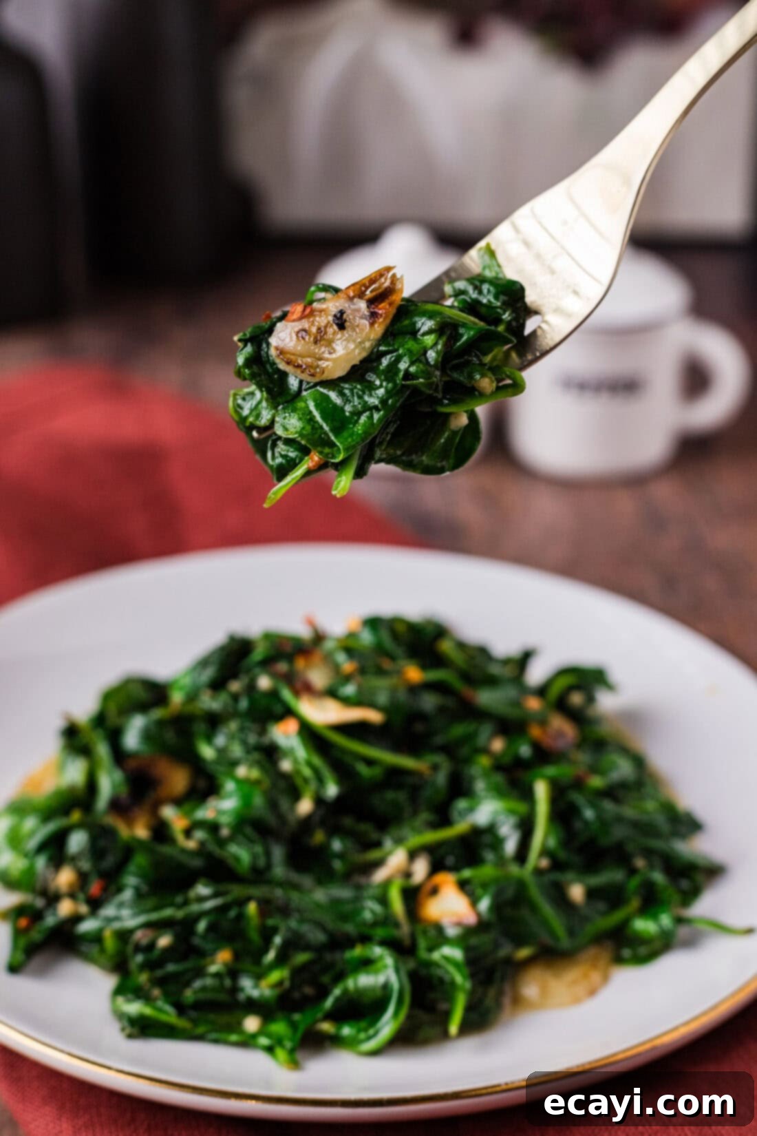 Wok-Kissed Spinach 2 Fork of Stir Fried Spinach held above a plate of Stir Fried Spinach
