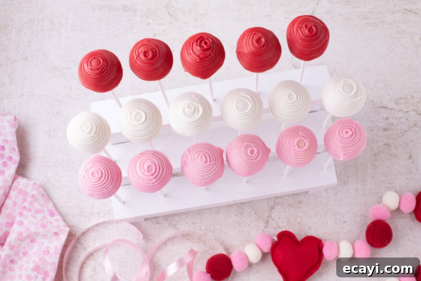 Sweetheart Cake Pops 11 Overhead view of several beautifully drizzled Valentine Cake Pops resting on a specialized stand