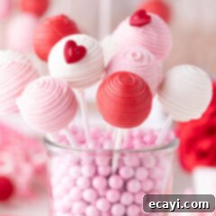 Sweetheart Cake Pops 13 Valentine Cake Pops resting in a clear glass container, showcasing their vibrant colors and festive sprinkles.