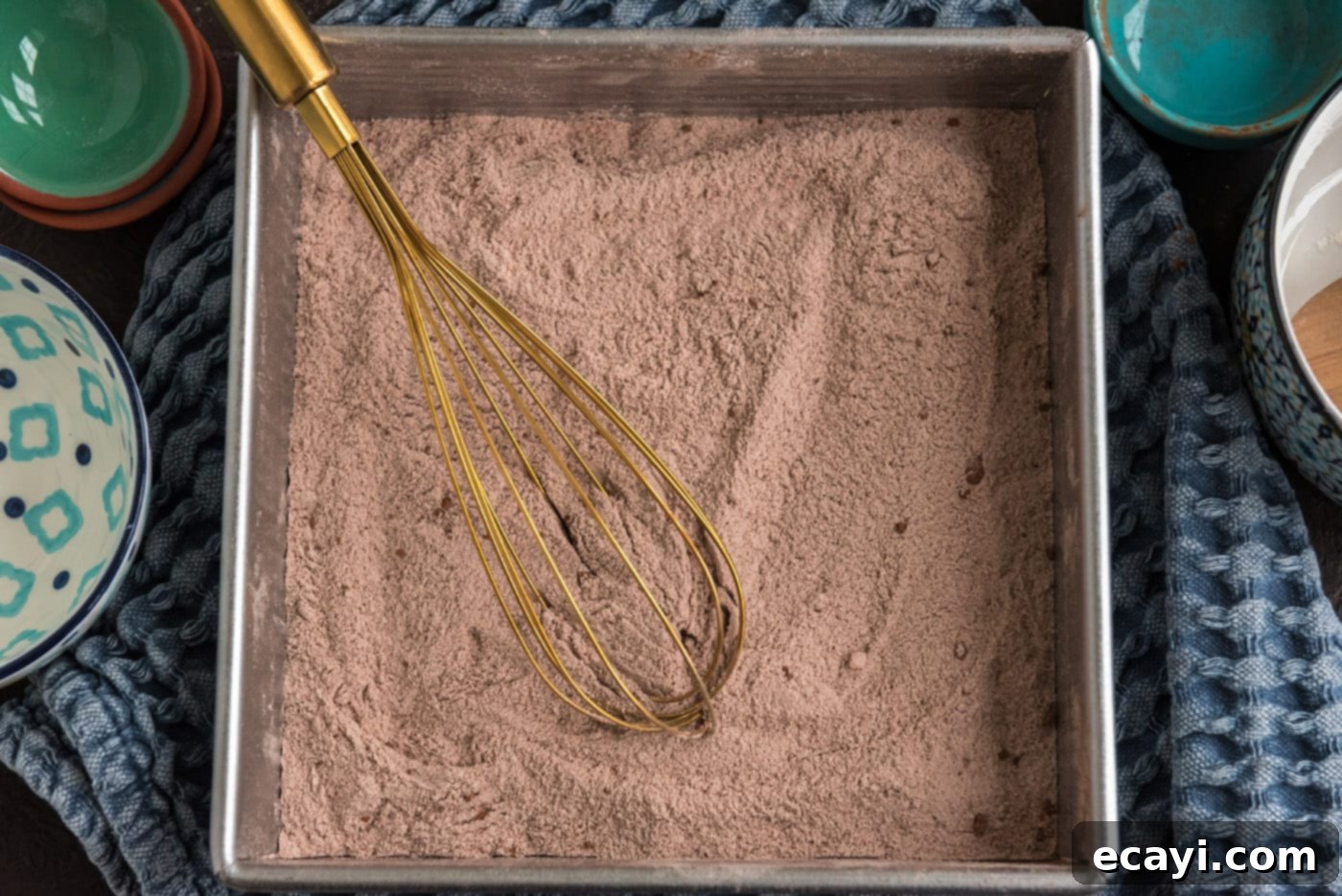 Miracle Mix Cake 6 dry cake ingredients in a metal baking pan with a whisk