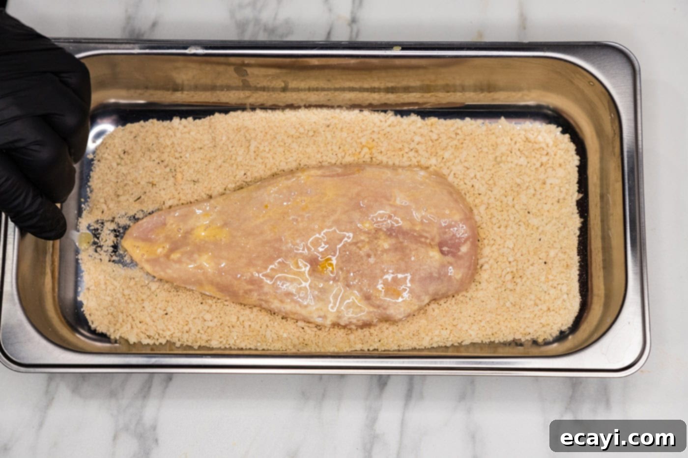 Golden Panko Chicken Cutlet 10 dredged chicken breast in a pan with panko breadcrumbs