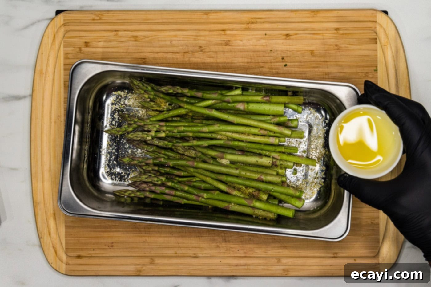 Bright Lemon Asparagus 6 hand holding olive oil in a bowl over asparagus