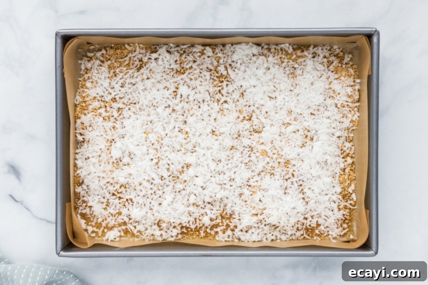 Pure Magic Dessert Bars 7 Shredded coconut layered over the graham cracker crumbs and butter in the baking pan.