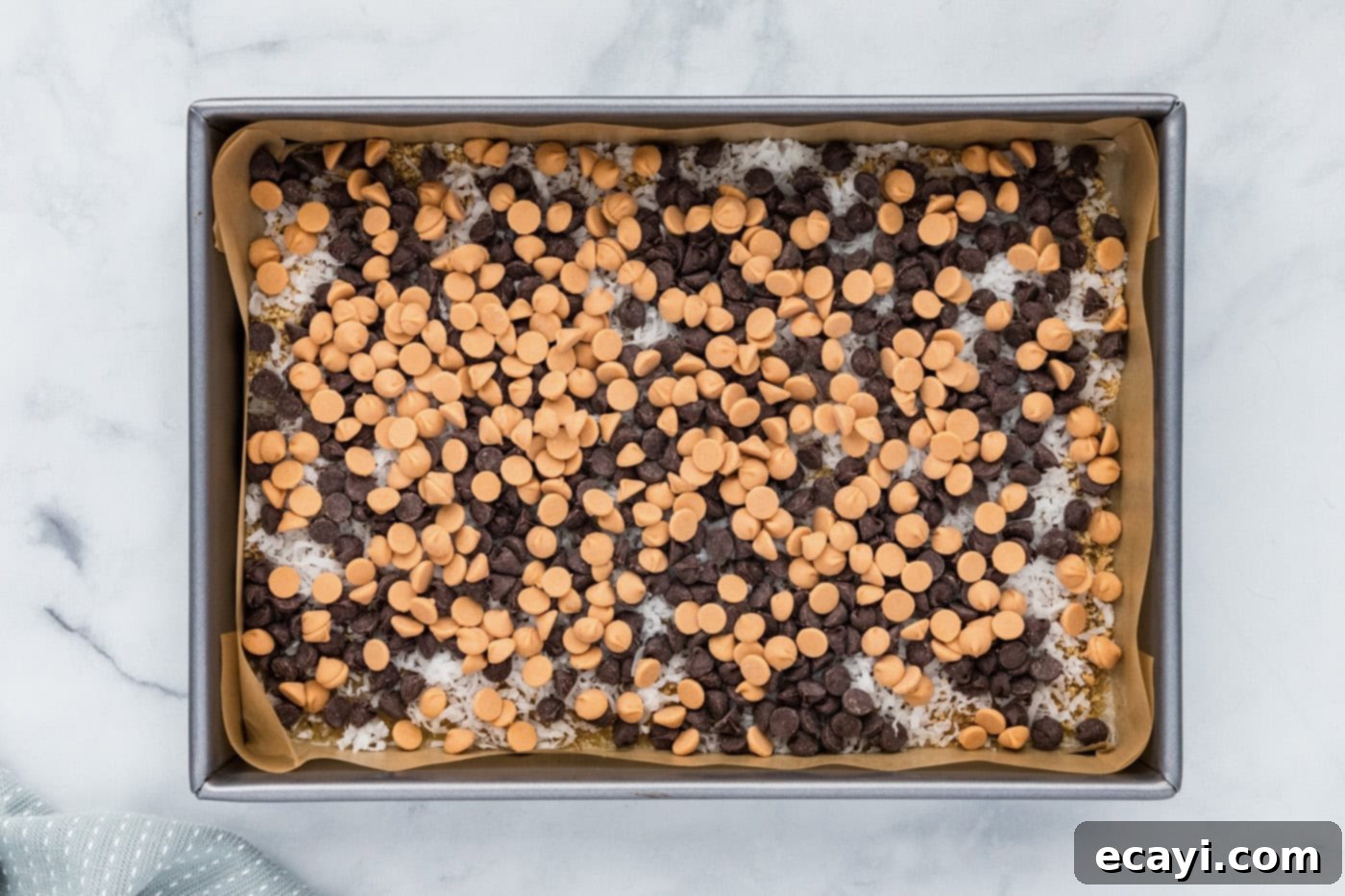 Pure Magic Dessert Bars 8 A vibrant layer of semi-sweet and butterscotch chocolate chips covering the shredded coconut and butter base.