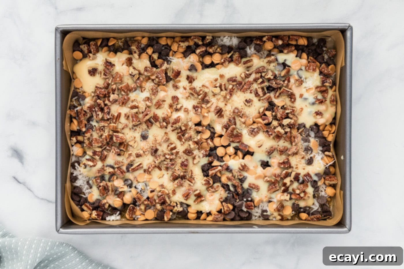 Pure Magic Dessert Bars 10 Chopped pecans sprinkled generously over the sweetened condensed milk layer in the baking dish.