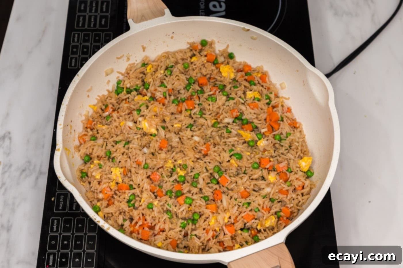 Golden Fried Rice Delights 11 Vegetable fried rice with eggs and vegetables mixed in a skillet, nearly complete