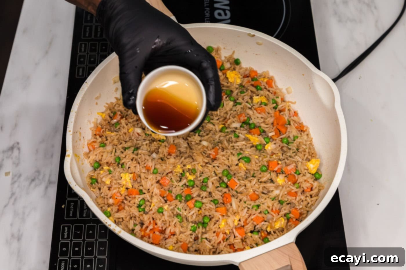 Golden Fried Rice Delights 12 Pouring sesame oil into vegetable fried rice in a skillet for final flavoring