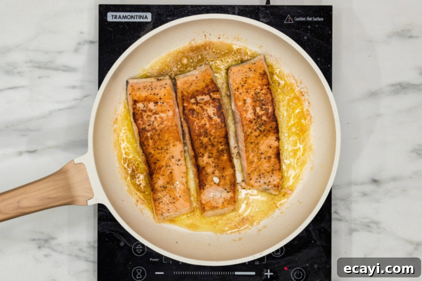 Creamy Tuscan Salmon 6 salmon filets cooking in a skillet with oil and butter