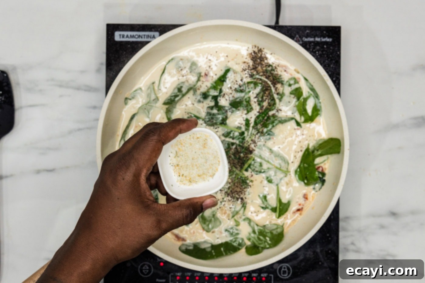 Creamy Tuscan Salmon 9 adding garlic salt to cream sauce with spinach in a skillet