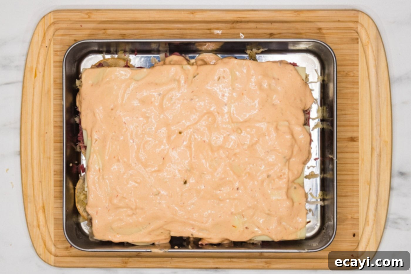 Reuben Bites 8 Thousand Island dressing drizzled over the Swiss cheese layer of the Reuben sliders.