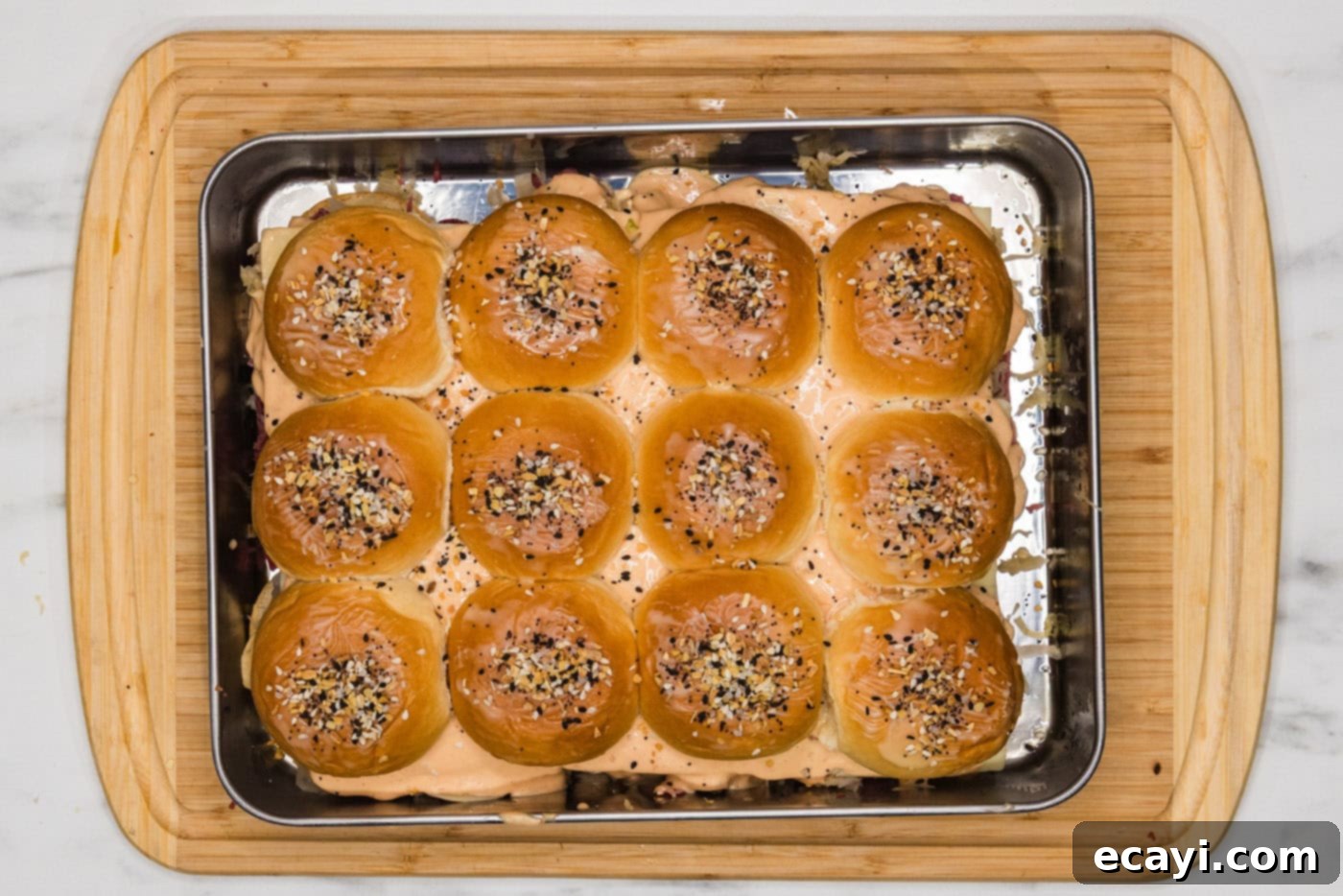 Reuben Bites 9 Reuben sliders assembled with top buns, brushed with butter, and sprinkled with Everything Bagel seasoning.