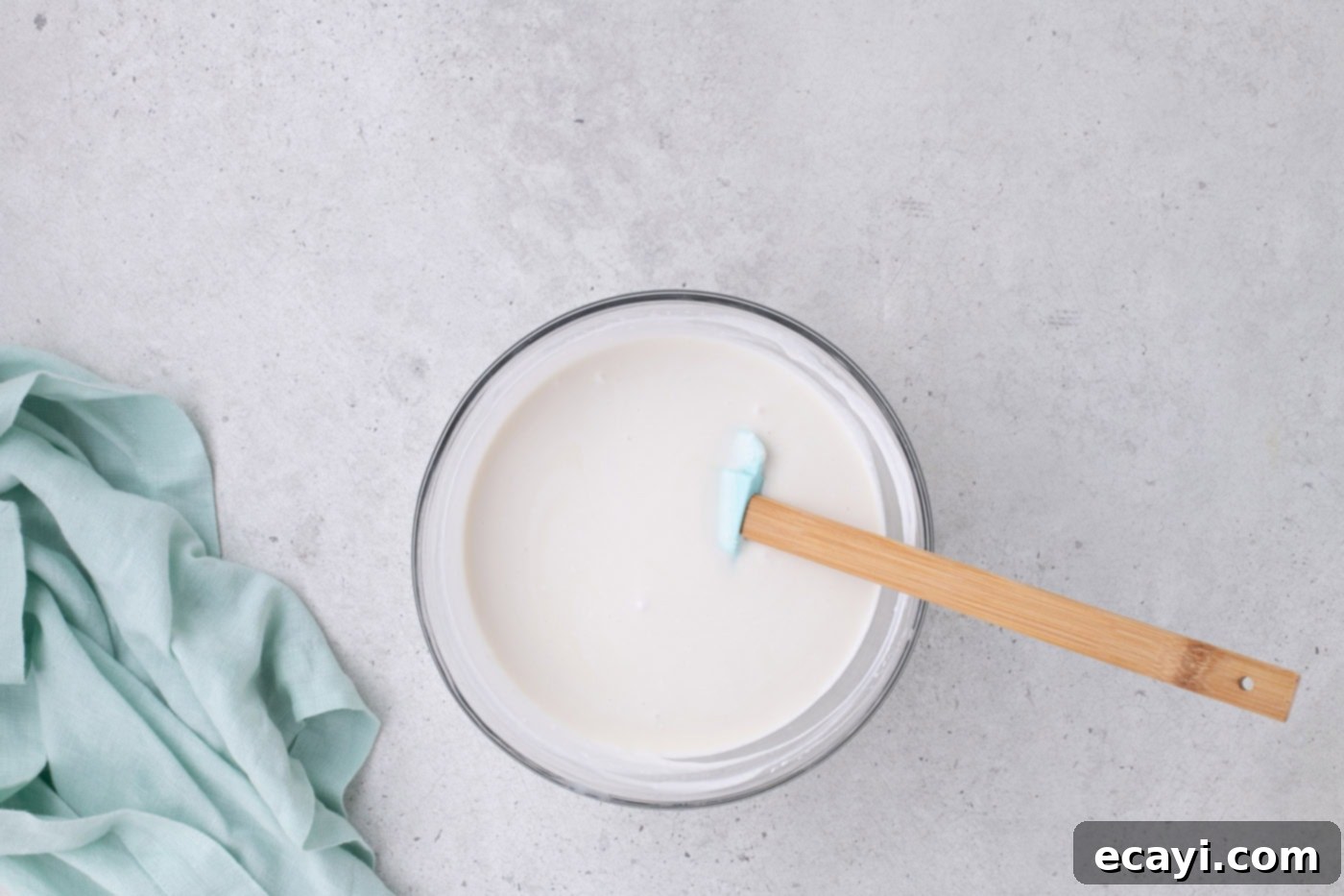 Tropical Coconut Infusion Cake 7 Coconut cream and sweetened condensed milk being stirred together in a bowl, creating a smooth, white filling.