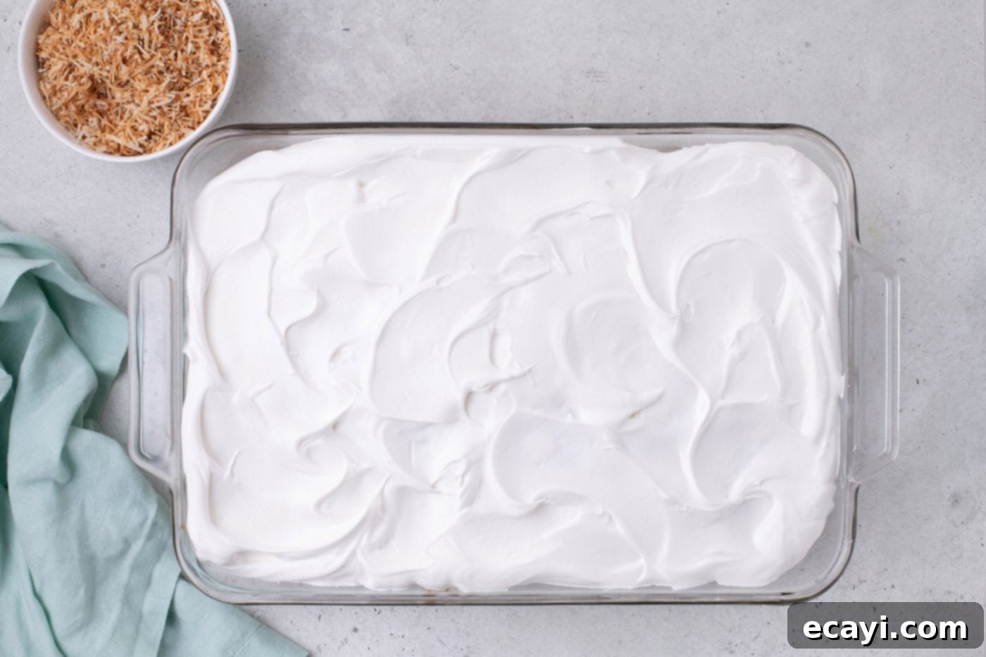 Tropical Coconut Infusion Cake 10 Whipped topping spread smoothly over the coconut poke cake, ready for garnish.
