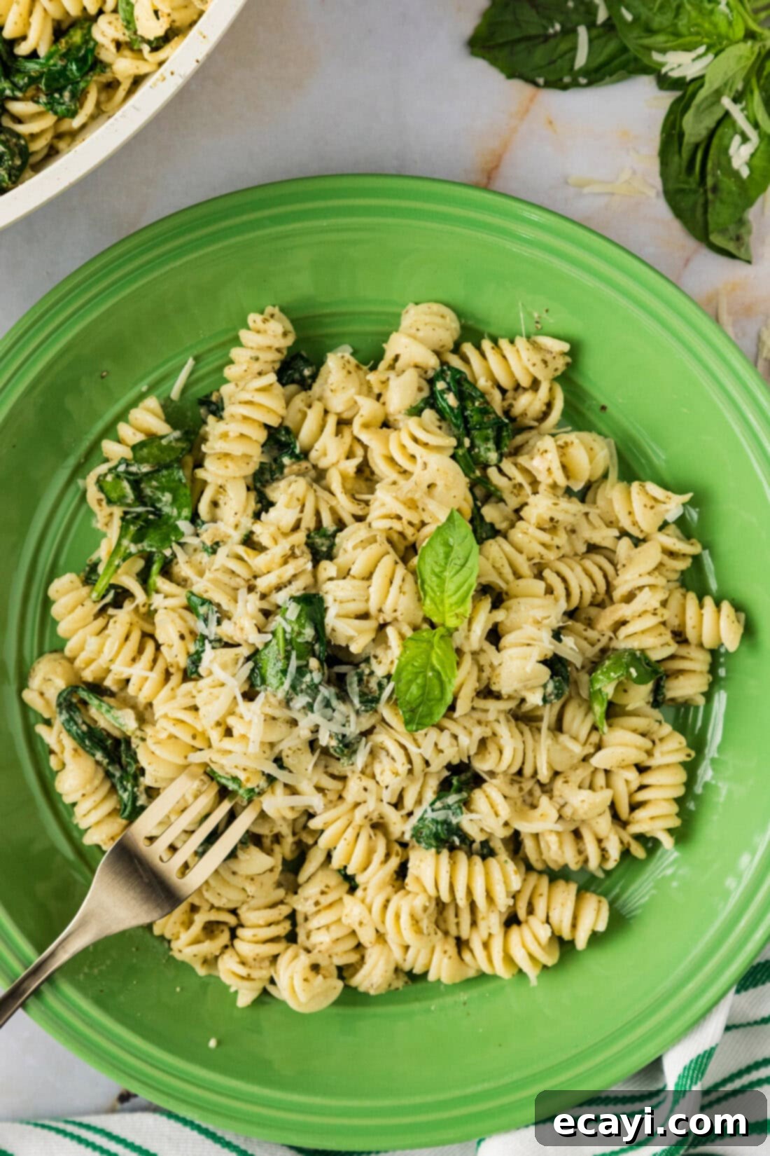 Pesto Perfection 2 Plate of Pesto Pasta with a fork in it, garnished with fresh herbs and cheese