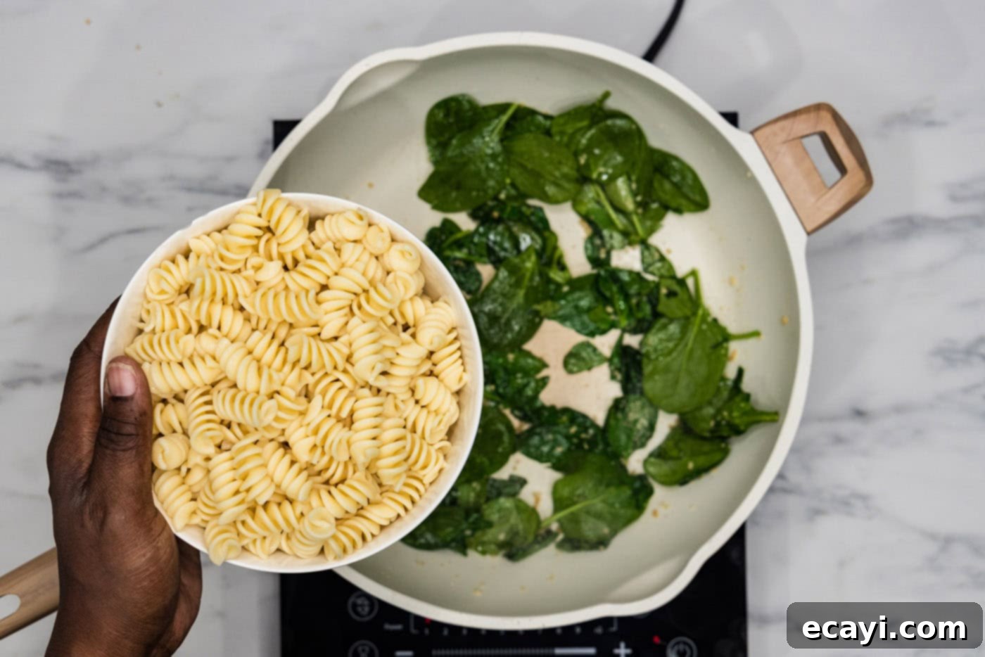 Pesto Perfection 6 adding pasta to spinach in a skillet