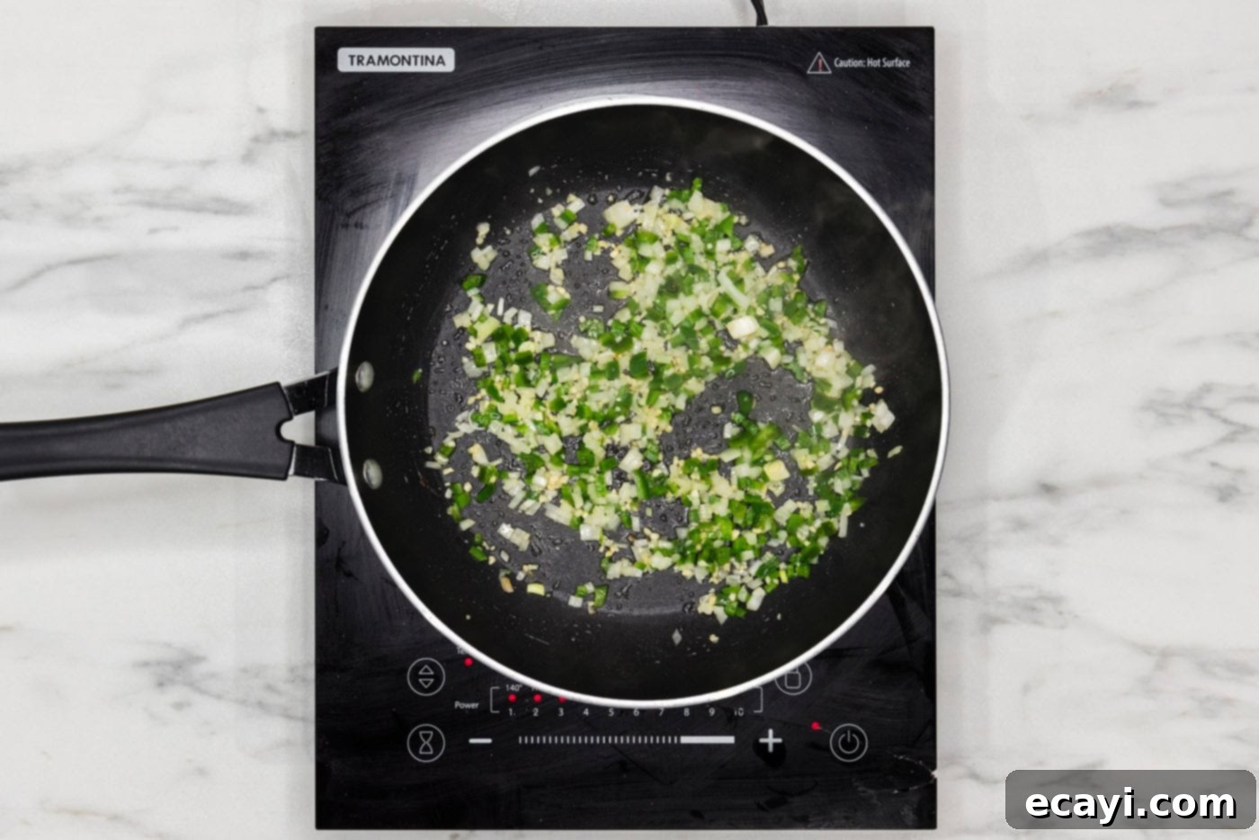 Taco Burger Fusion 5 Diced onion and jalapenos sizzling in a skillet, turning translucent.