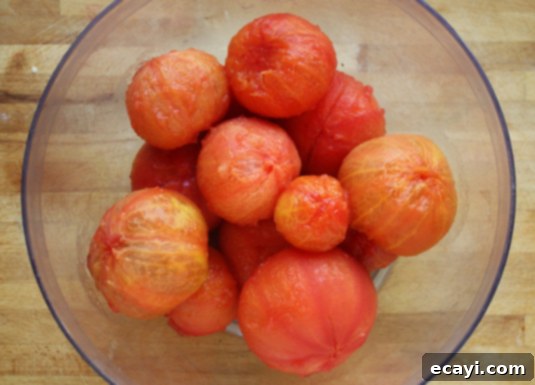 5 pounds of fresh and peeled garden tomatoes // FoodNouveau.com A large bowl overflowing with whole, peeled red garden tomatoes, glistening and ready for the next step in making fresh tomato sauce. These are perfect for a vibrant summer recipe.