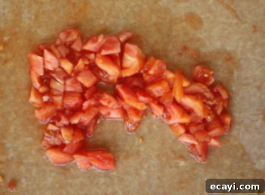 Peeled tomatoes, coarsely chopped // FoodNouveau.com A bowl of coarsely chopped, peeled red tomatoes, including their seeds and juices, prepped for simmering into a delicious fresh tomato sauce. The vibrant red color suggests peak ripeness.