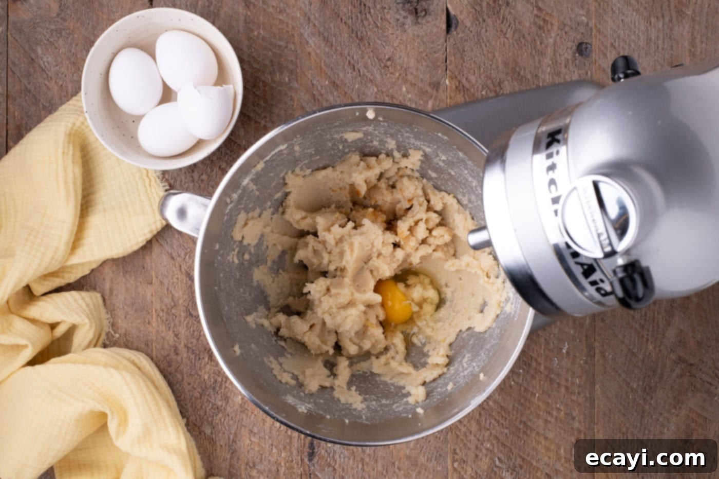 Zesty Lemon Blueberry Bliss 6 Adding eggs one by one to the butter and sugar mixture in a mixer