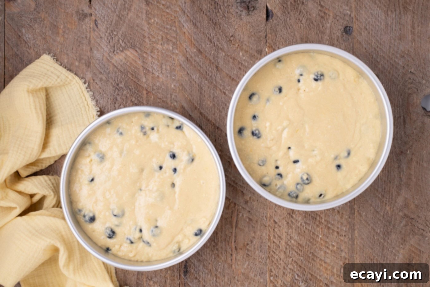 Zesty Lemon Blueberry Bliss 9 Lemon blueberry cake batter evenly divided into two round baking pans, ready for the oven