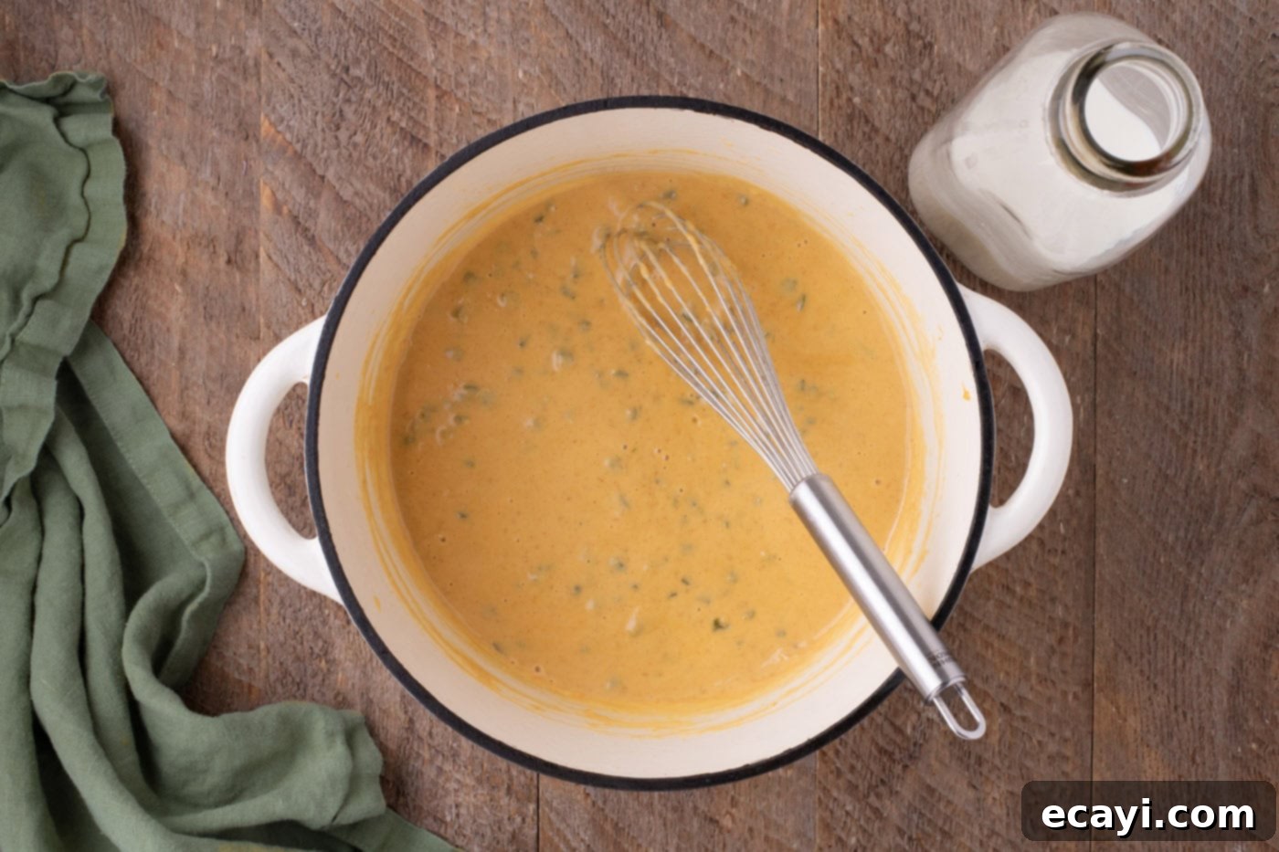 Spicy Cheesy Popper Mac 7 cheese sauce in a pot with a whisk
