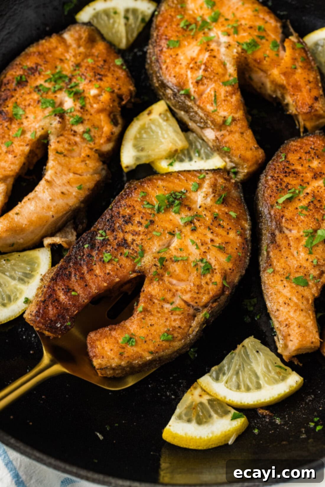 The Art of Perfect Salmon Steaks 2 Close up photo of a perfectly pan-seared Salmon Steak on a spatula resting in a skillet, showcasing its golden-brown crispy skin and succulent, flaky flesh.