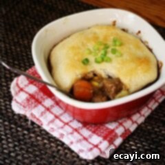 Homestyle Beef Biscuit Pot Pie 11 A close up photo of a half eaten beef stew biscuit pot pie resting on a red and white napkin.