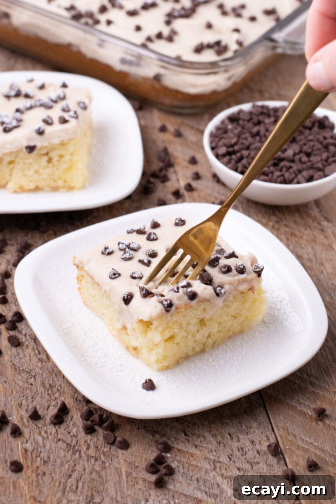 Creamy Ricotta Cannoli Poke Cake 2 Fork cutting into a slice of Cannoli Poke Cake, showing layers of moist cake and creamy topping.