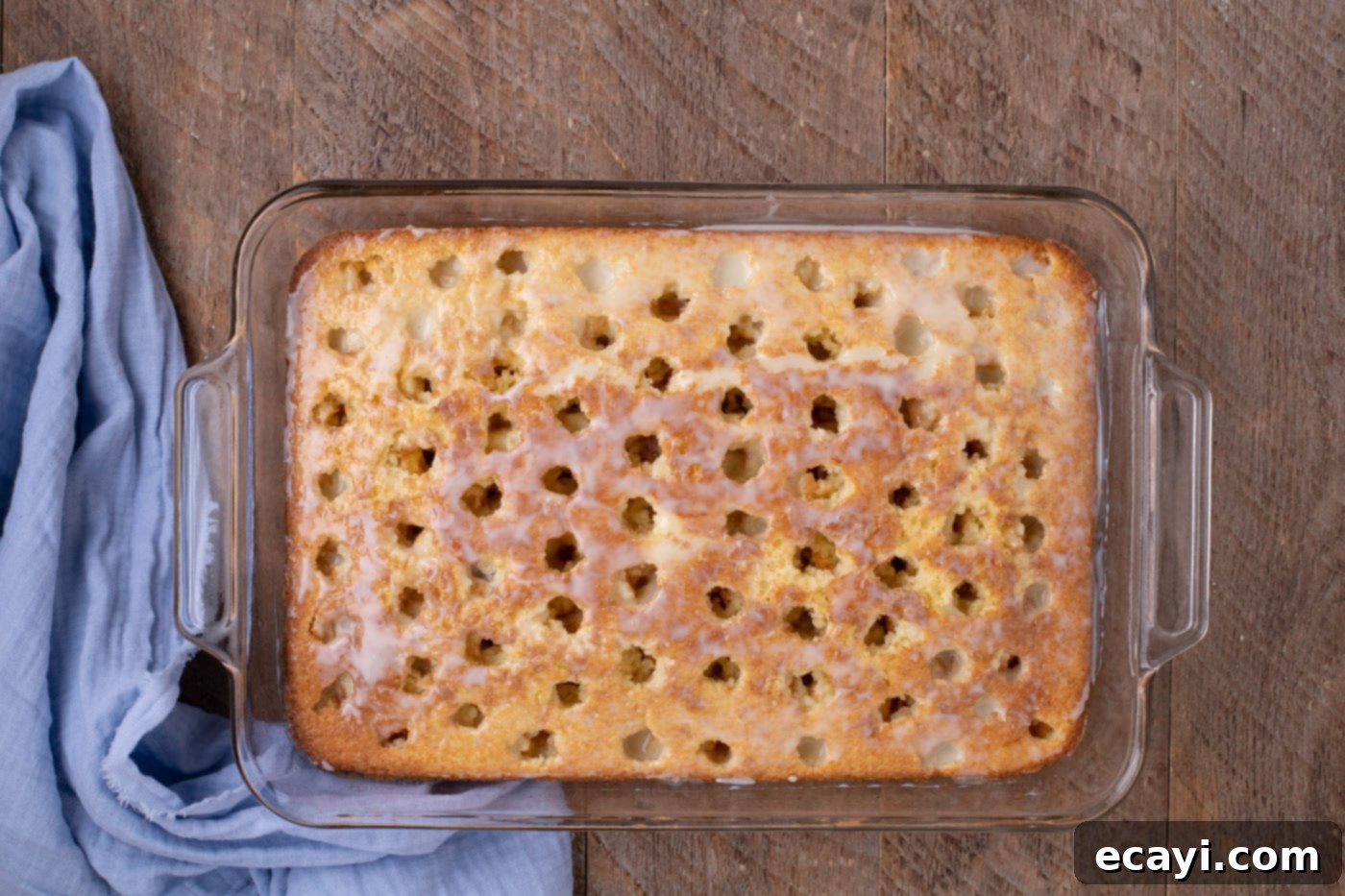 Creamy Ricotta Cannoli Poke Cake 8 Sweetened condensed milk being spread over a poke cake