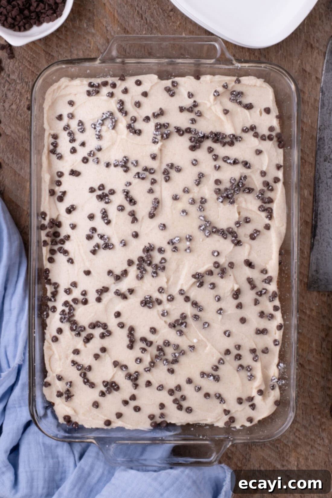 Creamy Ricotta Cannoli Poke Cake 10 Overhead photo of a full Cannoli Poke Cake garnished with chocolate chips and powdered sugar.
