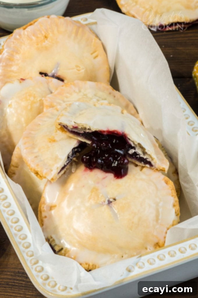 Making blueberry hand pies is fun and easy, and using a refrigerator pie crust dough cuts down on the work. Mini blueberry pies are delicious! blueberry mini pie broken open showing filling inside