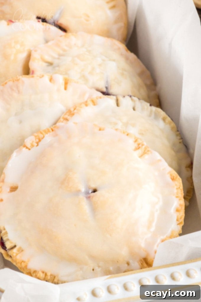 Making blueberry hand pies is fun and easy, and using a refrigerator pie crust dough cuts down on the work. Mini blueberry pies are delicious! glazed hand pies in a dish