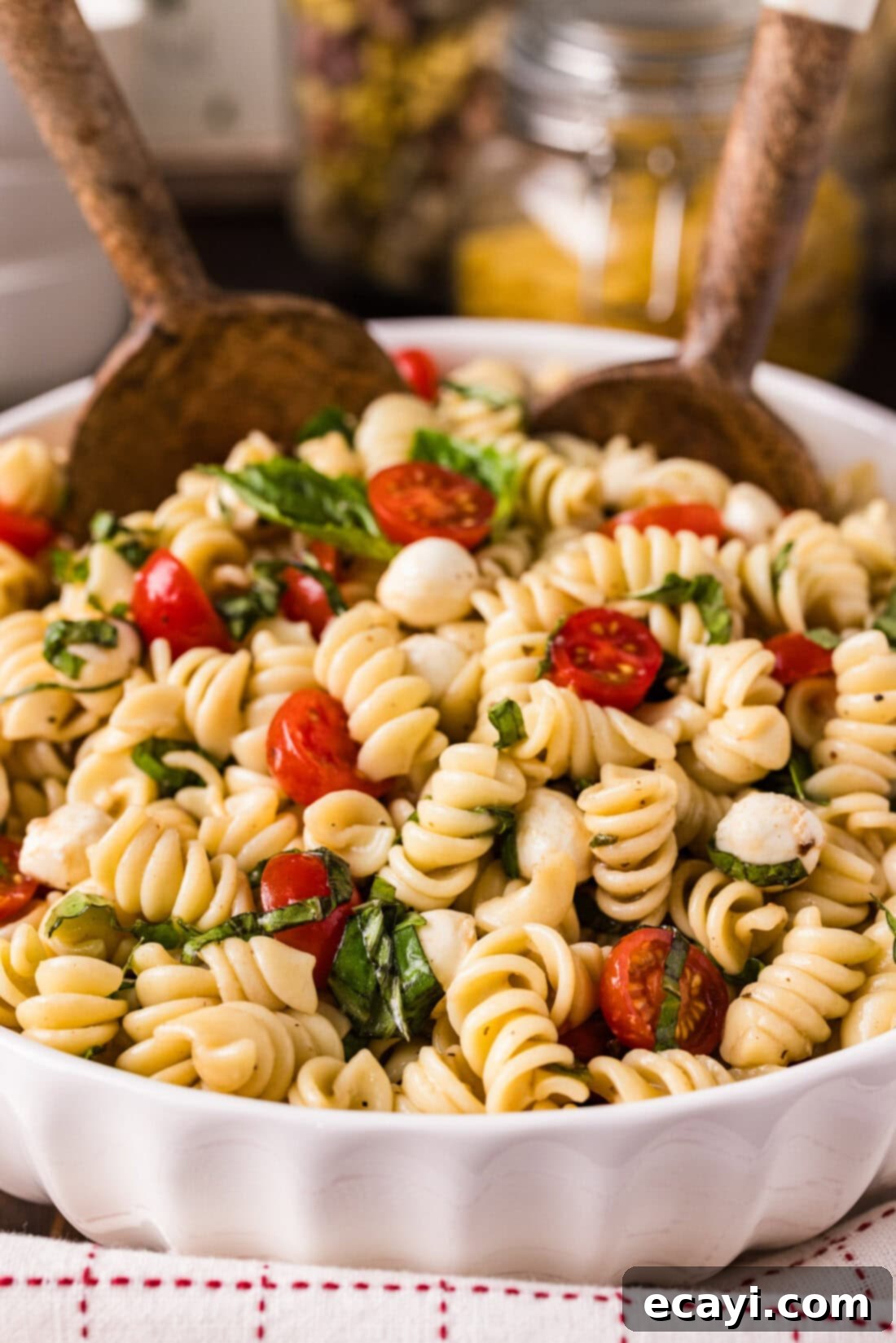 Caprese Pasta Delight 2 Two spoons in a bowl of Caprese Pasta Salad, showcasing its vibrant colors and fresh ingredients.