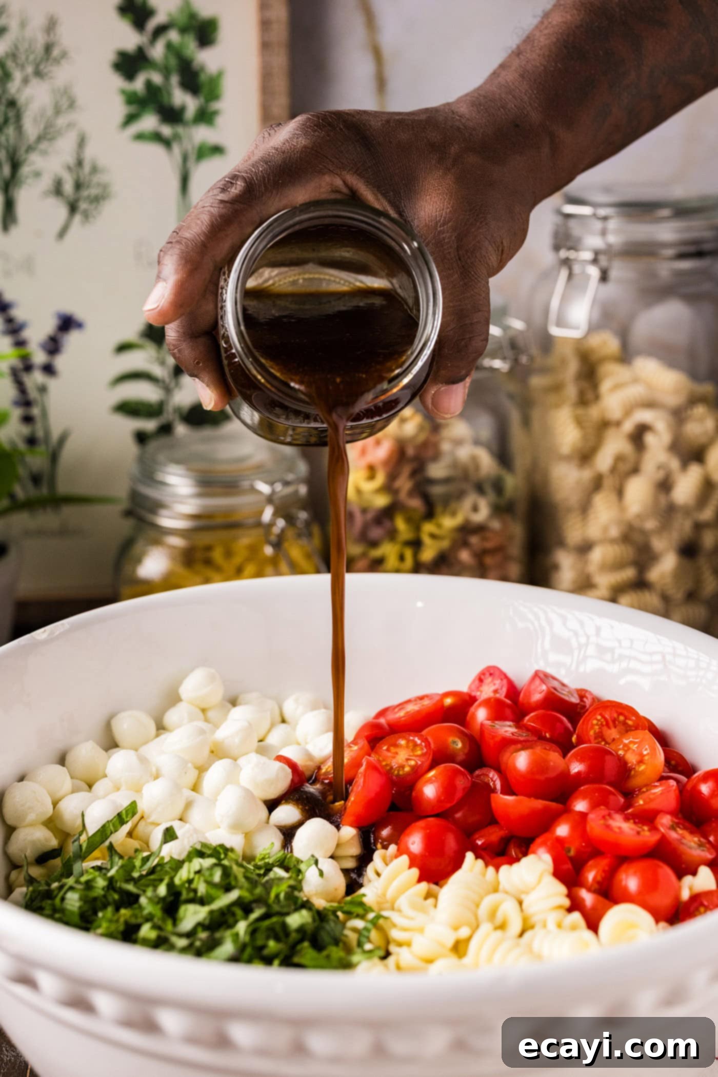 Caprese Pasta Delight 6 Pouring homemade balsamic vinaigrette over the vibrant Caprese pasta salad in a bowl, showing the dressing mixing with the ingredients.
