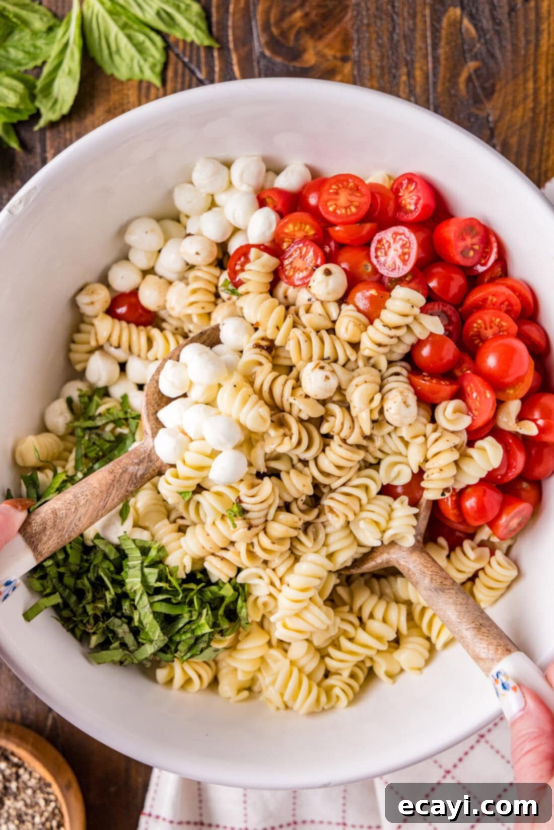 Caprese Pasta Delight 7 Caprese Pasta Salad being mixed in a serving bowl, showcasing the vibrant colors and appealing texture.