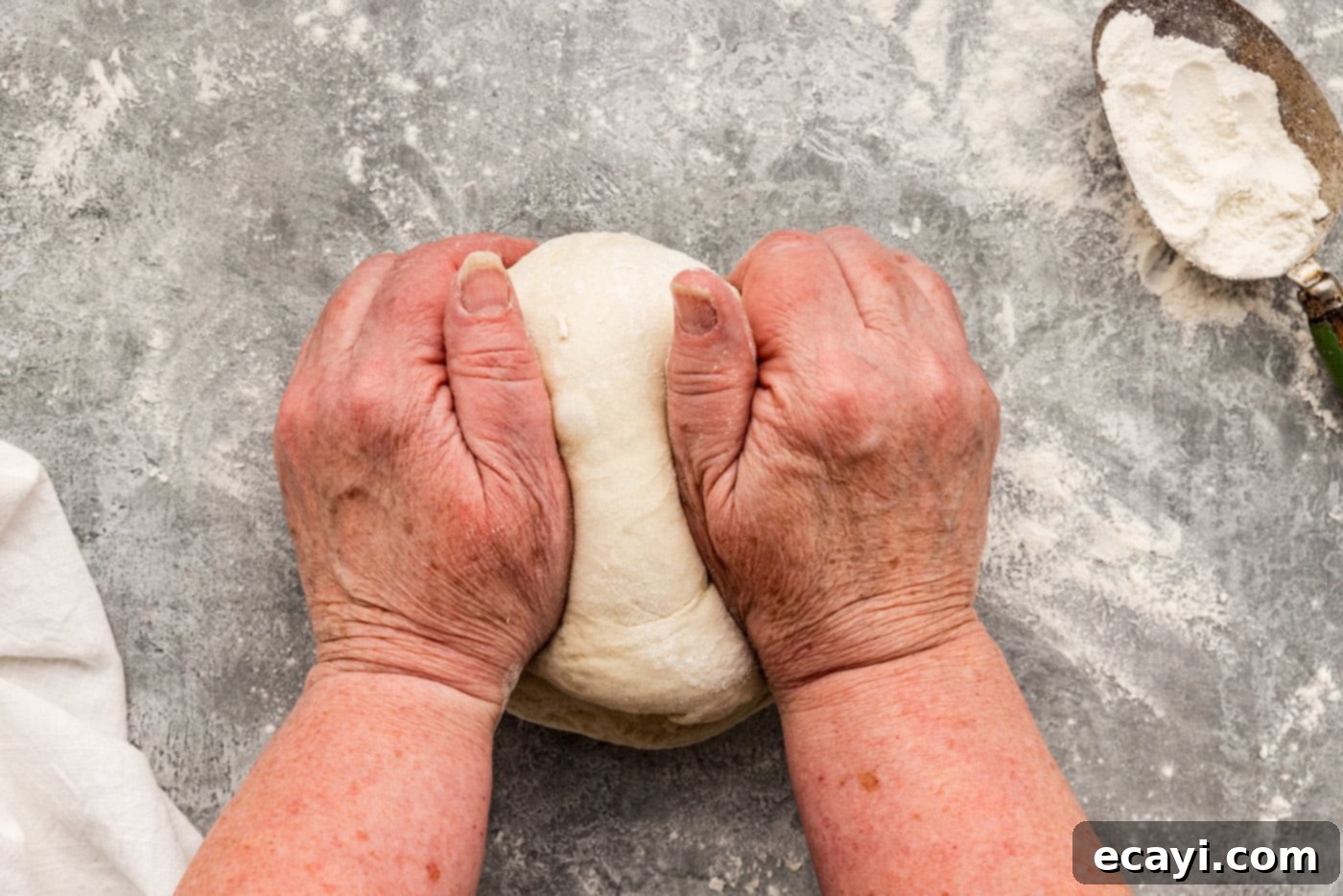 Endless Warm Garlic Breadsticks 11 Hands kneading breadstick dough on a floured surface, demonstrating the kneading technique.