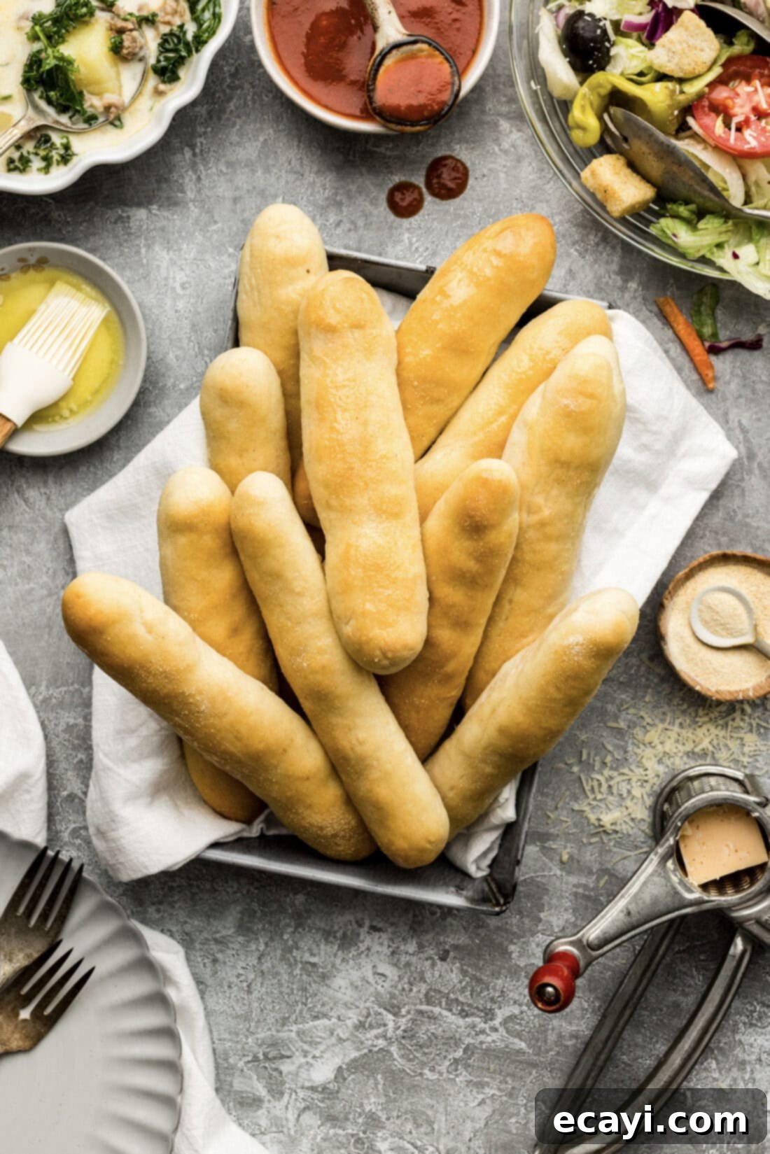 Endless Warm Garlic Breadsticks 15 A cozy basket filled with warm Olive Garden Breadsticks, served alongside a bowl of soup and a fresh salad, creating a complete meal.