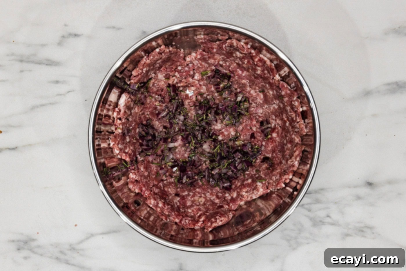 Crafted Lamb Burgers 6 Ground lamb mixed with sautéed onions, garlic, rosemary, and spices in a bowl, ready to be formed into patties