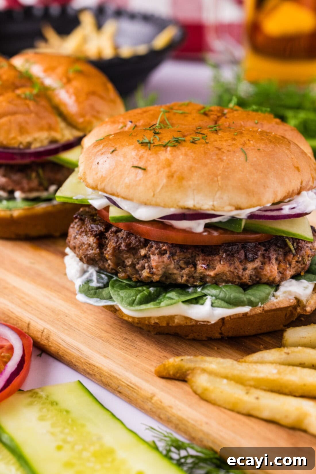 Crafted Lamb Burgers 8 Close up photo of a gourmet lamb burger on a wooden board, with tzatziki sauce and fresh vegetables blurred in the background