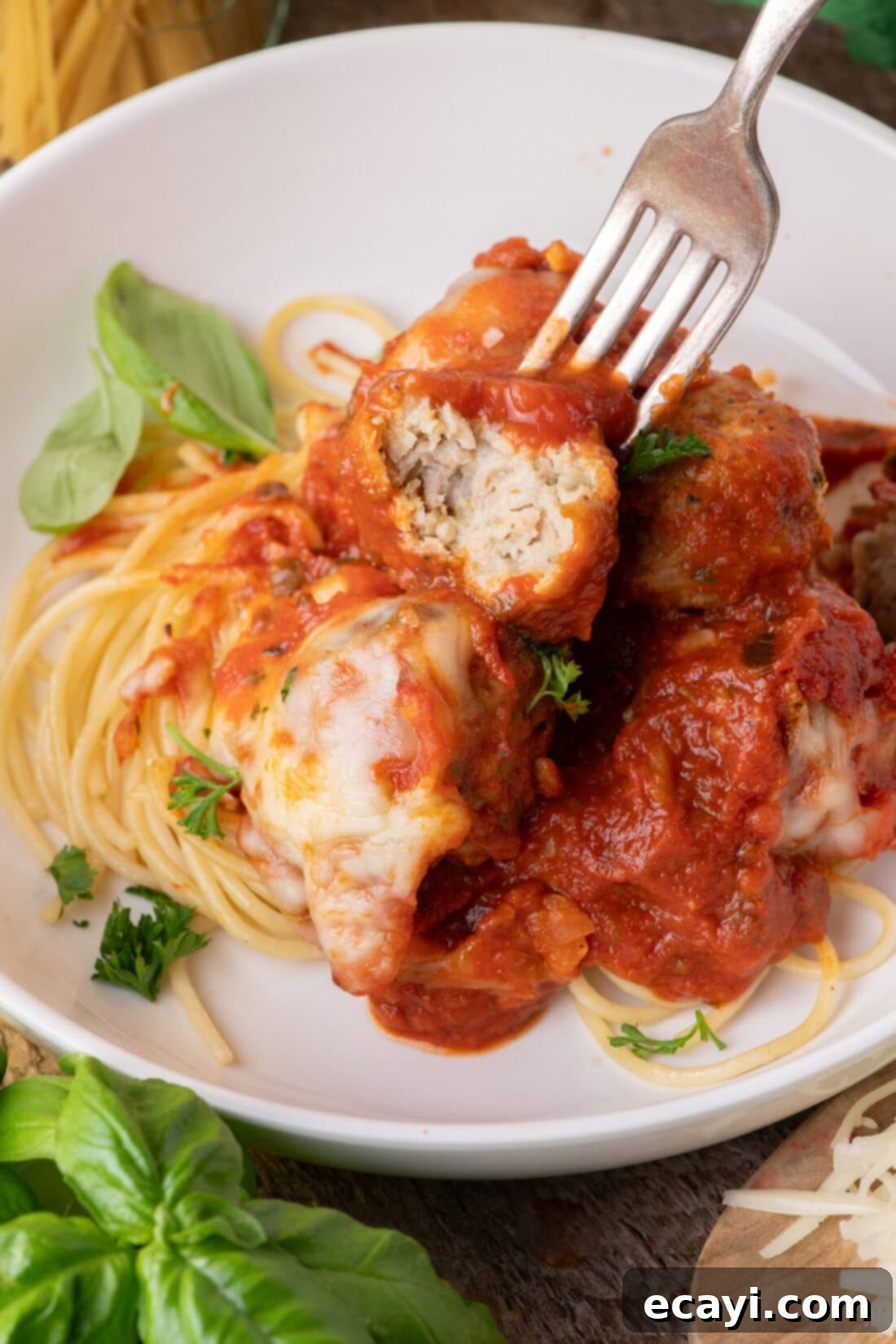 Cheesy Chicken Parm Bites 3 Fork holding half of a Chicken Parmesan Meatball over spaghetti and meatballs