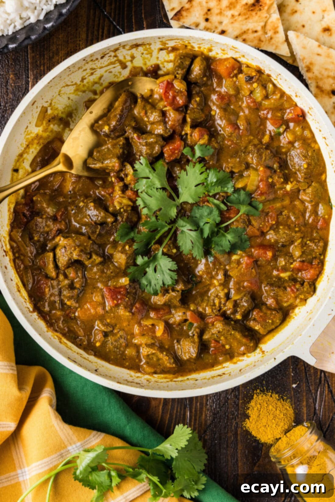 Tender Beef Curry 3 A large skillet brimming with simmering, rich Stovetop Beef Curry and a wooden spoon