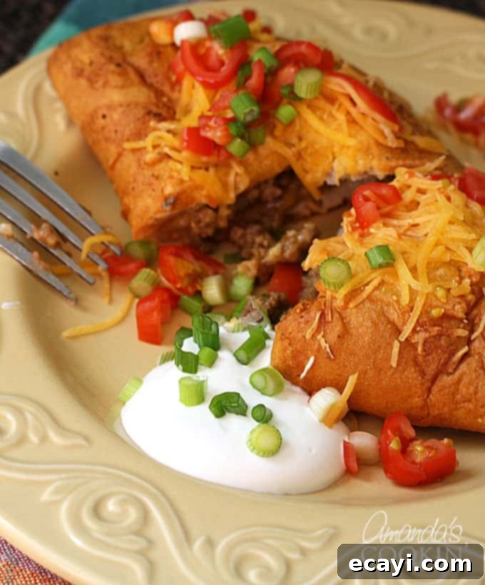 These taco empanadas are easy to make and are a great weeknight meal. Taco hand pies are perfect for leftover taco meat! Easy to eat on the go as well! cut in half taco empanada with fresh garnishes