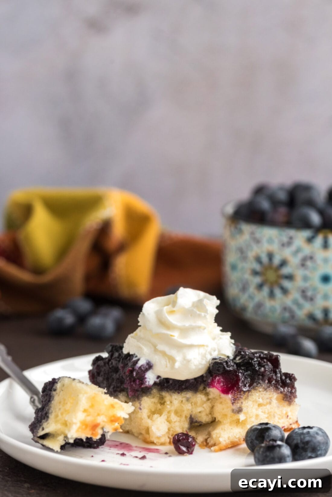 Blueberry Flip Cake 15 Piece of Easy Blueberry Upside Down Cake on a plate with a bite removed